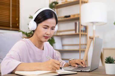 Kafede dizüstü bilgisayar kullanan odaklanmış kadın, notlar yazma, çekici kız öğrenci öğrenme dili, online web semineri izleme, sesli dinleme, e-öğrenme eğitim konsepti