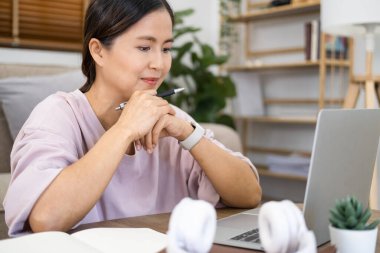 Online öğrenimde odaklanmış Asyalı bir kadın, dizüstü bilgisayardan eğitici webinar izlemekten zevk alıyor. Müşterilerle video görüşmesi yapan gülümseyen genç bir iş kadını. Evde çalışan genç bir kız öğrenci..