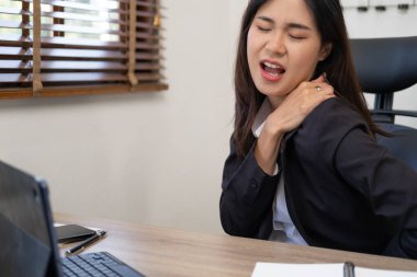 Ofis sendromu konsepti. Genç Asyalı iş kadını bilgisayarla uzun süre çalıştıktan sonra boyun ağrısı çekiyor.