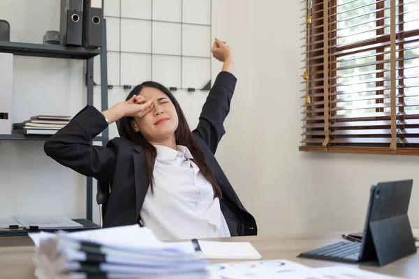 Businesses or working lady is stretch themselves or lazily for relaxing on their desk while doing their work in the office.