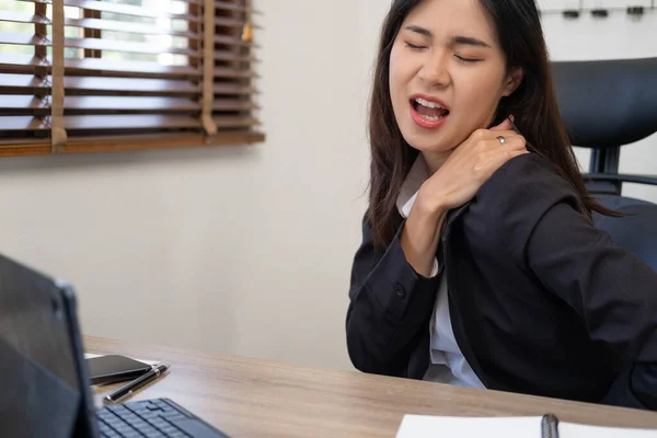 Office syndrome concept. Young asian businesswoman feeling pain in neck after working on computer laptop for a long time