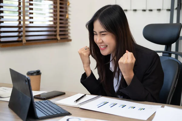 Beautiful Asian girl celebrate with laptop, success happy pose. E-commerce, internet technology, or startup small business concept. Modern office . Happy excited successful woman triumphing in office.