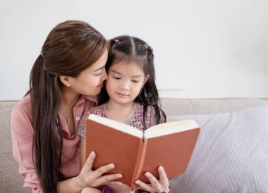 Anne ve kızı birlikte kitap okuyarak zaman geçiriyorlar. Çocukların gelişimi ve kaliteli zaman kavramı.