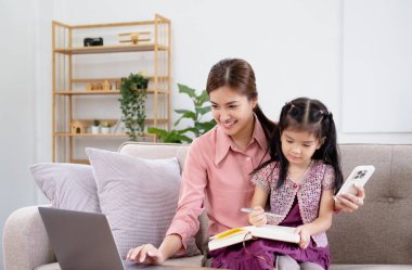 Aile konsepti. Annem çalışıyor ve kızına da bakıyor..