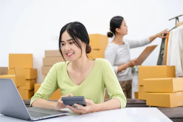 stock image Asian woman entrepreneur using calculator for calculating financial expense at home office, Prepare product for packaging process, Online selling, Internet marketing, E-commerce concept.