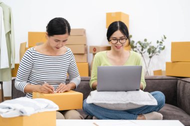 Çevrimiçi genç kadın satıcı, e-ticaret için çalışıyor. İş sahibi satış sezonunda online siparişleri kontrol ediyor ve paketliyor. Çevrimiçi alışveriş ve e-ticaret kavramı.