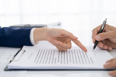 İş adamının kontrat imzalaması için kağıtları gösteren avukatın elleri. Avukat, yasal danışman olgun müvekkilin evrakları doldurmasına yardım ediyor, sağlık sigortası formu, vasiyet, imza yapıştırma. Belgeler.