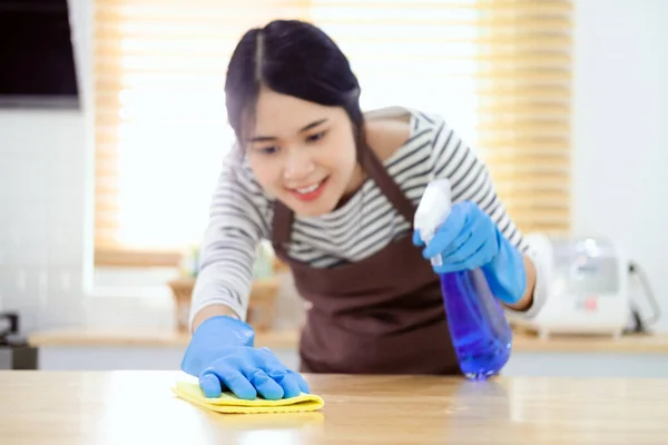 亚洲家庭主妇用毛巾和手套用消毒剂清洗厨房桌子表面 — 图库照片