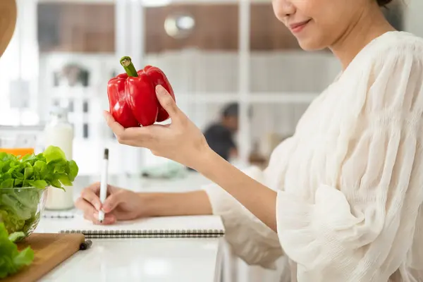 Diet, Dieting asian woman write diet plan right nutrition on table with fresh vegetables salad,  is different food ingredients in the green. Nutritionist of healthy, nutrition of weight loss.