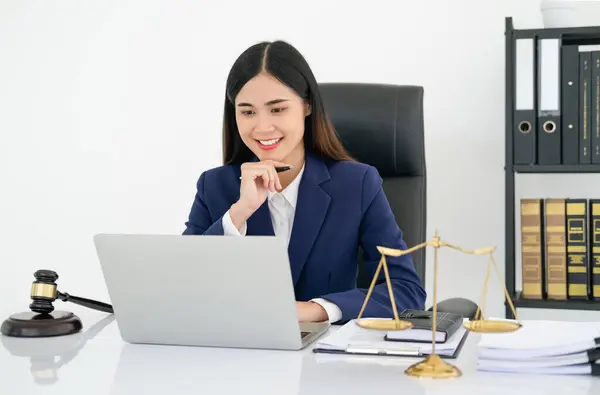 tavsiye ve adalet kavramı. Adalet terazileri, adalet çekici ve davacılık belgesi, kadın avukat elinde kalem, avukatlık bürosunda dizüstü bilgisayarla çalışıyor..