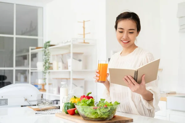 Woman reading recipe for simple summer salad in cookbook. Simple healthy food concept