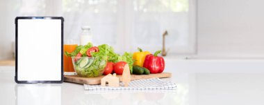 Vejetaryen sağlıklı sebze arka planında beyaz ekranı olan dijital tablet bilgisayar. Online market alışverişi uygulaması reklamları konsepti, yemek kitabı diyet tarifleri, yakın görüş.
