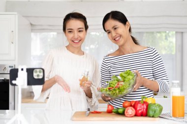 İki pozitif insan selfie kaydedip gülümsüyor ve mutfakta sağlıklı salata hazırlıyorlar.
