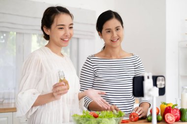 İki pozitif insan selfie kaydedip gülümsüyor ve mutfakta sağlıklı salata hazırlıyorlar.