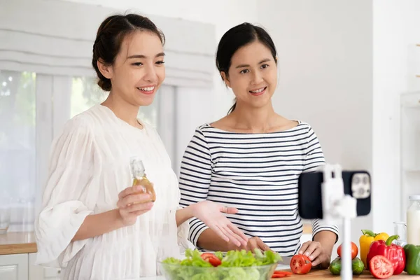 İki pozitif insan selfie kaydedip gülümsüyor ve mutfakta sağlıklı salata hazırlıyorlar.
