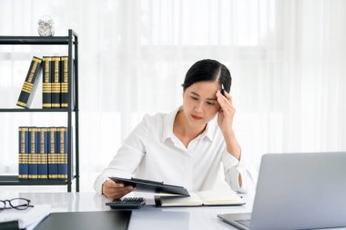 Odaklanmış Asyalı kadın kağıt belgelere bakıyor, iş ilişkilerini yönetiyor, vergileri özetliyor, gelecekteki yatırımları planlıyor, sadece merkez büroda muhasebe yapıyor..