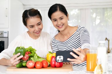 Asyalı kız arkadaşlar video blogu paylaşırken kameraya bakarlar. Z gençliği sağlıklı yemek pişirmekten hoşlanır. Akşam yemeği, öğle yemeği, eğlenceli eğlence, eğlence, eğlence, gülüş, rahatlama..