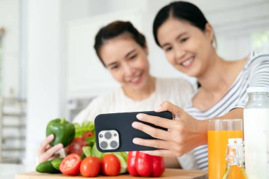 İki pozitif insan selfie kaydedip gülümsüyor ve mutfakta sağlıklı salata hazırlıyorlar.