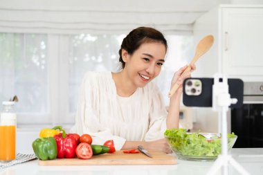 Genç ve neşeli bir kadın cep telefonuyla sağlıklı yemek ve yemek hakkında konuşuyor. Sağlıklı beslenme ve sosyal medyayı etkileme kavramı