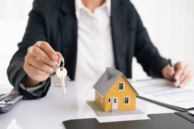 Emlakçı müşterilere örnek evler, ipotekli kredi sözleşmeleri veriyor. Kiralık bir ev alıp satmak için bir sözleşme yap. ve ev sigortası sözleşmeleri, ev kredisi konseptleri