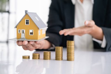 Gayrimenkul veya gayrimenkul yatırımı. Ev kredisi oranı. Emeklilik konsepti için para biriktiriyorum. Masada ev modeli olan bozuk para yığını. İş büyüme arkaplanı
