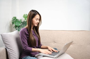 Bilgisayarlı bir kadın internetten e-posta haberlerini kontrol ediyor kanepeye oturuyor, internetten arkadaş arıyor ya da bilgisayar başında çalışıyor, blog yazıyor ya da Webinar izliyor, evde çalışıyor.