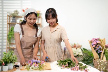 Çiçekçide tezgah başında buket yapan meslektaşlar. Asya insanları genç KOBİ sahibi mutlu bir gülümseme ev ofisinin açık çiçekçi çalışmalarının keyfini çıkarın.