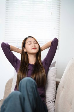 In cozy living room happy woman put hands behind head sitting leaned on couch female enjoy lazy weekend or vacation, housewife relaxing feels satisfied accomplish chores housework concept clipart