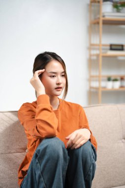 Alnına dokunan Asyalı kadın iş ya da ilişkiler yüzünden hayal kırıklığına uğramış, kanepeye oturmuş, dizlerini kucaklıyor, umutsuzluk ve endişe duyuyor, yalnızlık çekiyor, psikolojik sorunlar yaşıyor..