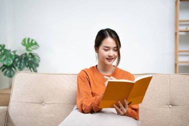 Oturma odasındaki koltukta oturan bir kadın notlar yazıyor.