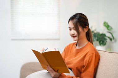 Oturma odasındaki koltukta oturan bir kadın notlar yazıyor.