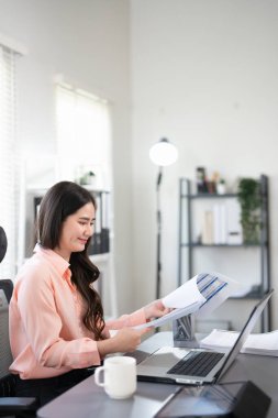 Genç, meşgul bir iş kadını yöneticisi, avukat ya da şirket çalışanı muhasebe kayıtları tutuyor mali verileri kontrol ediyor ya da dizüstü bilgisayarla çalışan pazarlama raporlarına bakıyor. Belge yönetimi