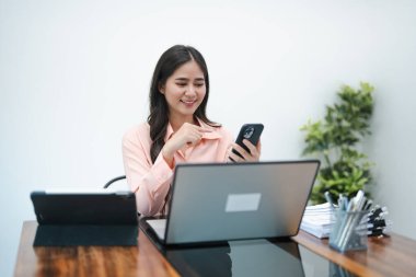 Genç meşgul Asyalı iş kadını lideri cep telefonu kullanıyor, akıllı telefona bakıyor modern şirket ofisinde çalışan finans piyasası uygulamasını kontrol ediyor. .