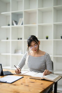 Kafede dizüstü bilgisayarı olan bir kadın üniversite öğrencisi ya da online eğitim için yazıyor. Kadın öğrenci, mutlu ve üniversite sınavları için çalışma veya düzeltme ve araştırma ile tatmin olmuş.