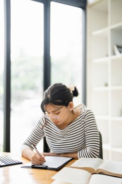Kafede dizüstü bilgisayarı olan bir kadın üniversite öğrencisi ya da online eğitim için yazıyor. Kadın öğrenci, mutlu ve üniversite sınavları için çalışma veya düzeltme ve araştırma ile tatmin olmuş.