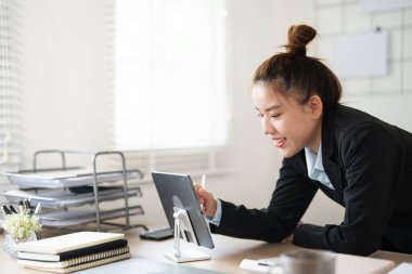 Tablet araştırma ve iş kadını internette çalışıyor. Teknoloji Asyalı profesyonel danışman masadaki e-postayı okuyor ve dijital uygulamayı kaydırmak için iletişim kuruyor.
