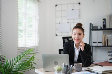 Genç düşünceli Asyalı iş kadını yönetici takım elbise giyiyor modern ofiste bilgisayar bilgisayarı ile çalışıyor, profesyonel planı düşünüyor, proje yönetimini düşünüyor, yeni iş fikirleri düşünüyor..