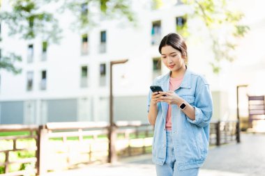 Üniversitede akıllı telefon kullanan bir kadın. Genç bir kadın internette geziniyor, dışarıda mesajlaşıyor ve iletişim kuruyor. Seyahat, moda, blog konsepti.