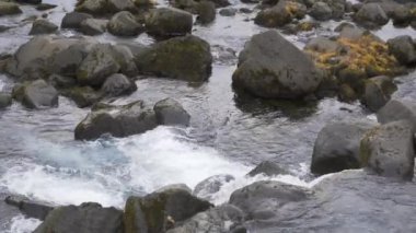 Dağ nehri kristal temiz suyla, su akıntısı İzlanda 'daki taşların üzerinden akıyor, yüksek kaliteli doğa görüntüsü 8k.