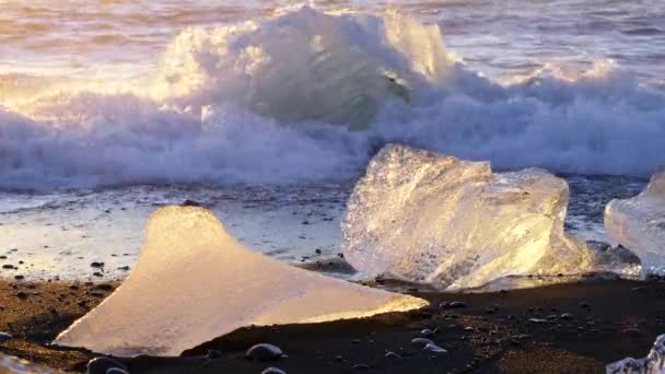 冰岛著名的钻石海滩 夕阳西下在黑色火山灰上闪耀的冰山 被海浪冲破的清澈冰雹 8K解析度4320P — 图库视频影像