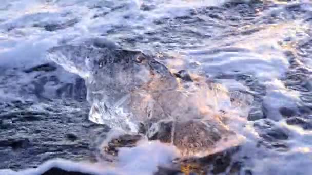 アイスランドの有名なダイヤモンドビーチ 日没時に黒い火山の砂に輝く氷山 海洋波に衝突した氷 8K解像度4320Pで撮影 — ストック動画