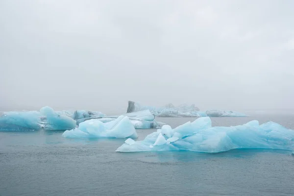 İzlanda Gölü 'nde eriyen buzullar sisli havada, saf mavi buzlar Jokulsarlon gölünde.