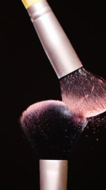Vertical Screen: Makeup Brushes Touch Each Other on Dark Background and Small Particles of Cosmetics, Beauty Concept Super Slow Motion Content Shot for Social Media. High quality footage
