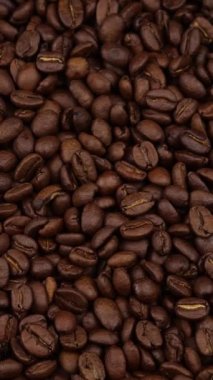 Vertical screen: Roasted vietnamese coffee bean. Fragrant coffee beans scrolls slowly around the camera. Slow Motion Close Up of Whole Roasted Coffee Beans.High angle view. Shot for Social Media. High