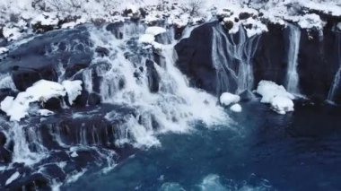 Hraunfossar, Famous Waterfall in Iceland, Snowy Ice Mountain River in Winter, Magical Outdoor Winter Time Location, Pure Glacial Water with a Huge Current. Clear Scenic Landscape Aerial View.