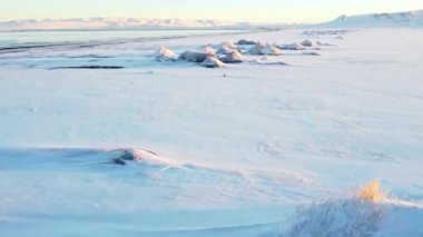Winter Iceland Landscape at Sunrise. Unusual Snow Covered Hills On The Ocean Shore. Beautiful Abstract Aerial View. Popular Tourist Destination. Travel Europe. 4k. High quality 4k footage