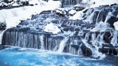 Waterfall in Iceland, Snowy Mountain and Cold River in Winter. Magical Outdoor Winter Time Location, Blue Glacial Water with a Huge Current. Pure Scenic Landscape. Hraunfossar. Shot in 8k Resolution.