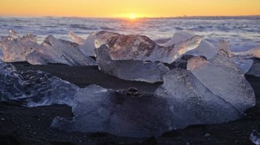 Famous Diamond Beach in Iceland, Icebergs Shining on Black Volcanic Sand at Sunset, Clear Ice Crashed by Ocean Waves, Shot in 8K Resolution 