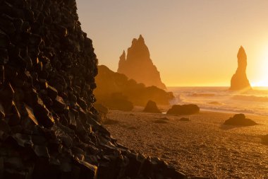 Black Sand Beach In Iceland. Sunset over Volcanic Cliffside. Stunning Ocean Coast. Unusual Pure Nature. Famous Tourist Location near Vik. Traveling in Iceland. Shot in High Resolution.