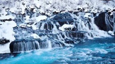 Waterfall in Iceland, Snowy Mountain and Cold River in Winter. Magical Outdoor Winter Time Location, Blue Glacial Water with a Huge Current. Pure Scenic Landscape. Hraunfossar. Shot in 8k Resolution.